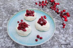 Ik heb toch een feestelijk nagerecht voor jullie. Deze pavlova krans met stoofpeertjes zal het super goed doen als dessert met de feestdagen. En het fijne ervan is dat je het meeste werk een dag van tevoren kunt doen, zodat je op de avond zelf bijna geen werk hebt aan dit zalig nagerecht. En zeg nou zelf, het ziet er toch feestelijk uit met die mooie donkerrode stoofpeertjes?  Pavlova  Pavlova’s zijn leuk en helemaal niet moeilijk om te maken. En het ziet er altijd feestelijk en indrukwekkend uit. Een pavlova bestaat uit een meringue, dit wordt gemaakt van stijfgeklopte eiwitten en suiker. Je lepelt het in een vorm op een bakplaat en bakt dit dan op lage temperaturen in de oven. De topping bestaat meestal uit stijfgeslagen room en vers fruit. Dit kan je allemaal van tevoren klaarmaken en dan hoef je de pavlova alleen nog maar af te maken vlak voordat je het gaat serveren. Ideaal dus als dessert om een etentje thuis.  Het lekkerste is als de meringue krokant van buiten is en lekker smeuïg vanbinnen. Dit krijg je door op het laatst azijn en maïzena door de stijfgeslagen eiwitten te mengen. En door de meringue op lage temperatuur te bakken in de oven, waarna deze het liefst de hele nacht in de oven (met de deur op een kier) verder uithardt.   Je kunt een grote pavlova, kleine eenpersoons pavlova’s maken of een krans zoals deze. Die doet het natuurlijk goed met de Kerst.  Ik heb de pavlova nu afgetopt met slagroom, maar je kunt ook mascarpone, een mengsel van mascarpone en slagroom of een mengsel van slagroom met hangop erop serveren.  Zomers kan je lekker vers rood fruit zoals aardbeien, frambozen, rode bessen of tropisch fruit zoals verse mango, ananas en/of passiefruit erop doen.  En in het najaar of ’s winters zijn deze stoofpeertjes, bramen, cranberrycompote en/of verse vijgen erg lekker.  Tips:  De meringue kan je al een paar dagen vooruit maken. Wikkel het in huishoudfolie en vervolgens in folie en bewaar op een koele droge plek. De slagroom op de meringue heb ik opgeklopt met ‘maar’ twee zakjes vanillesuiker. Meer suiker is niet nodig, omdat de meringue en de stoofpeertjes al heel veel suiker bevatten. Het recept van de stoofpeertjes* vind je hier.   Recept Pavlova krans met stoofpeertjes: